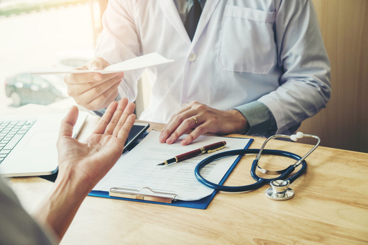 A doctor writing a diagnosis and handing it to a female patient