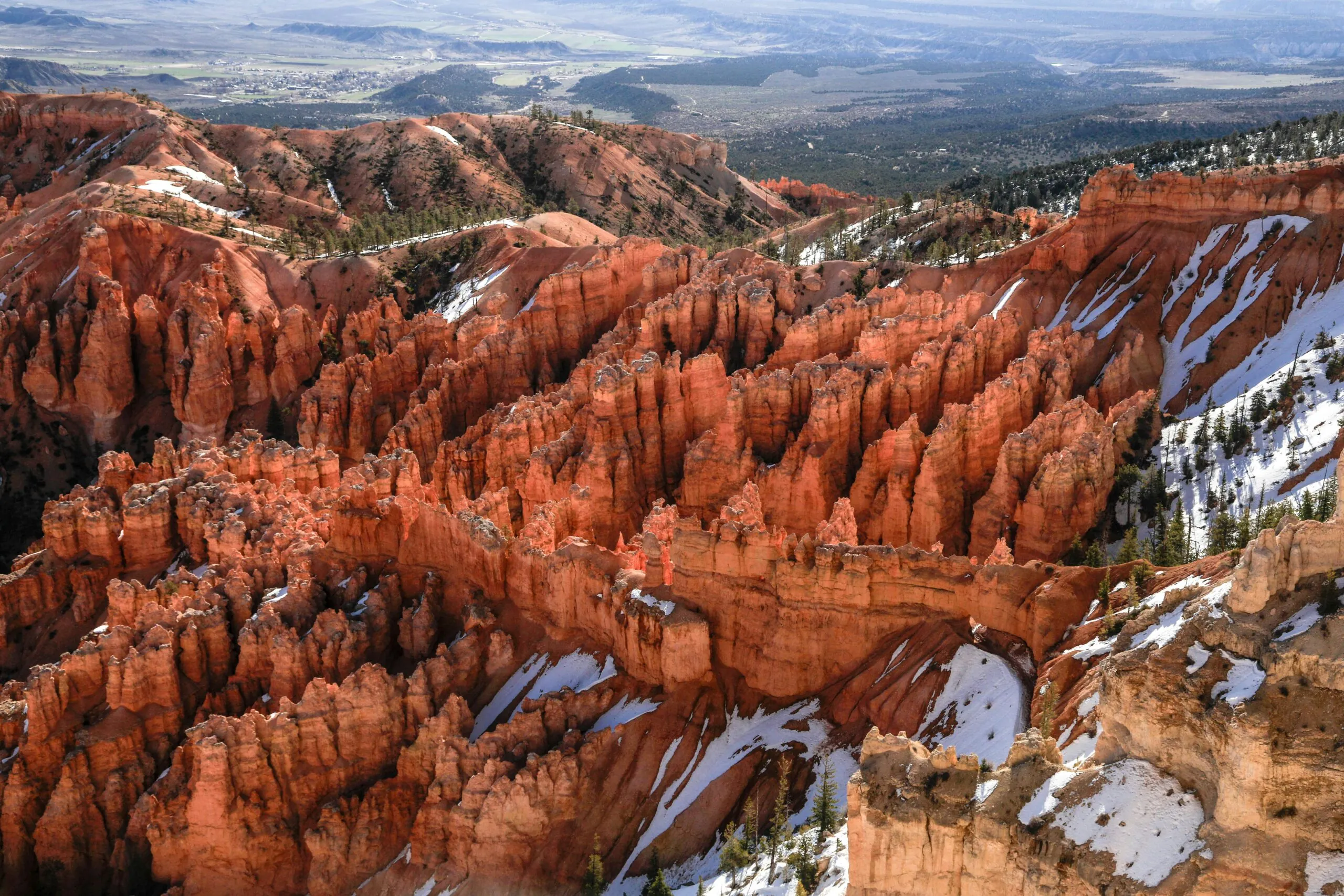 The red and orange mountain tops and cliffs of Bryce Canyon covered in snow.